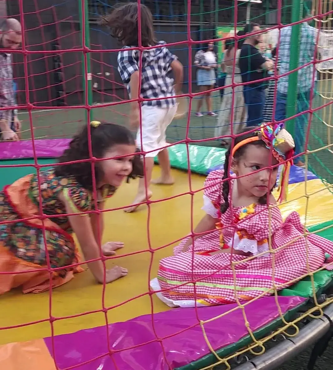 Crianças fantasiadas na cama elástica em festa junina