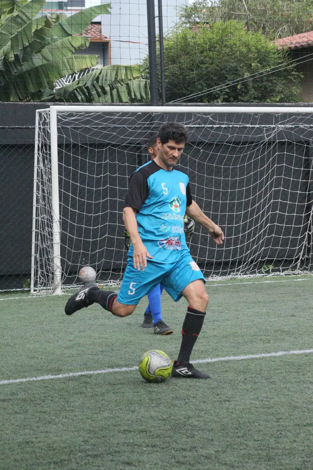 Jogador prepara o chute no campo society