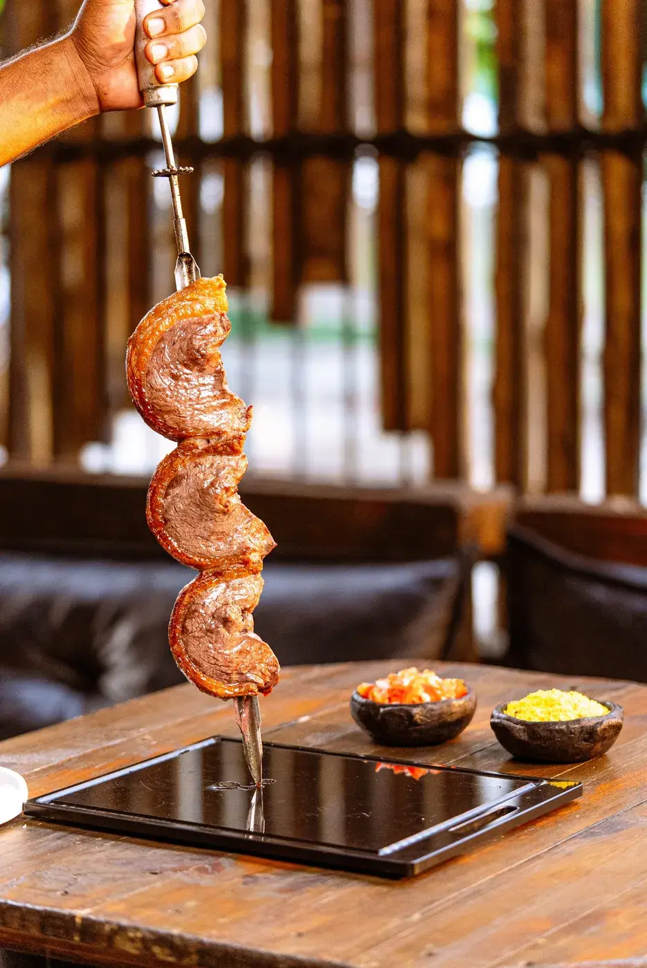 Espeto de picanha servido na mesa com farofa e vinagrete