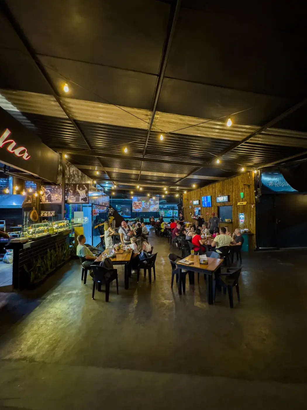 Salão do restaurante com mesas e telões