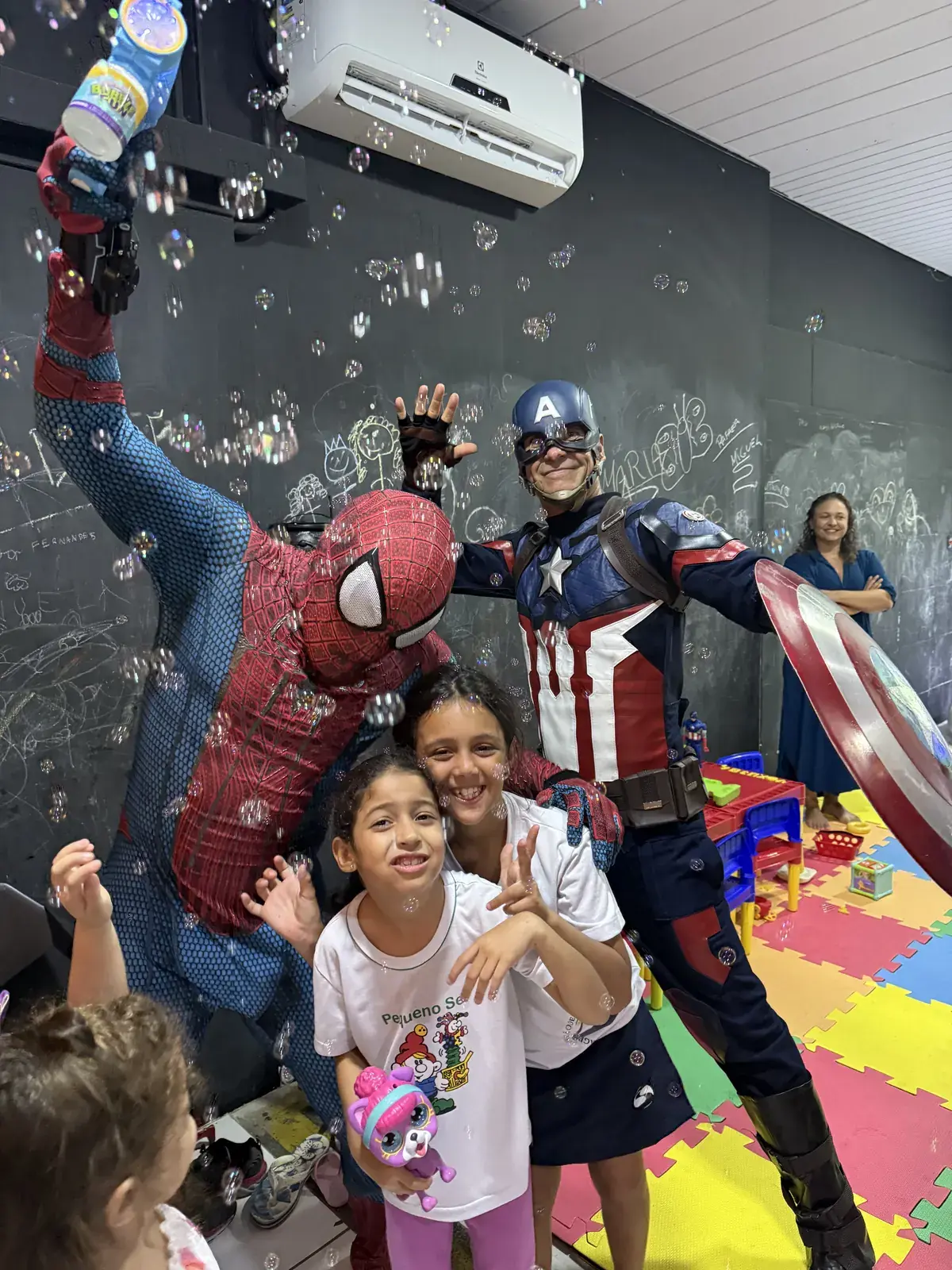 Crianças brincando com o Homem-Aranha e o Capitão América na brinquedoteca